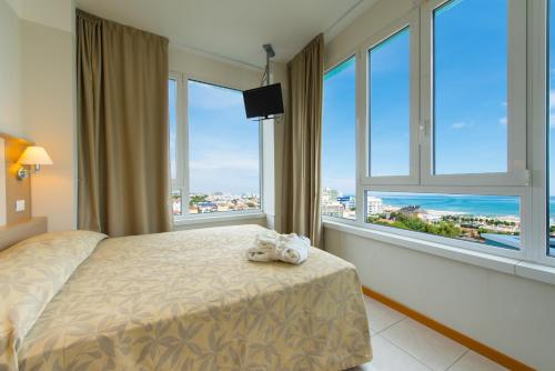 a bedroom with a bed and large windows at Hotel Cristallo in Riccione