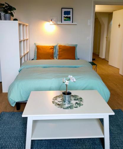 - un lit avec une table blanche et une fleur dans l'établissement Résidence Services Château Saint Pierre Oursin, à Vimont