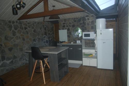 Una cocina con una mesa y un refrigerador blanco. en Le p'tit Zoréol, en Le Tampon