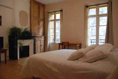 a bedroom with a bed with white sheets and windows at Appartement de charme au cœur d une cité médiévale in Villefranche-de-Conflent