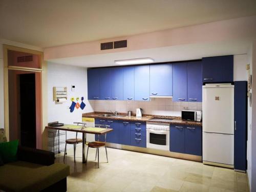 una cocina con armarios azules y una mesa. en Apartamento en primera línea de Playa Las Canteras, en Las Palmas de Gran Canaria