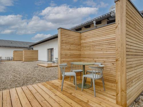 a wooden fence with a table and chairs on a deck at Limehome Bodenmais Bahnhofstraße in Bodenmais