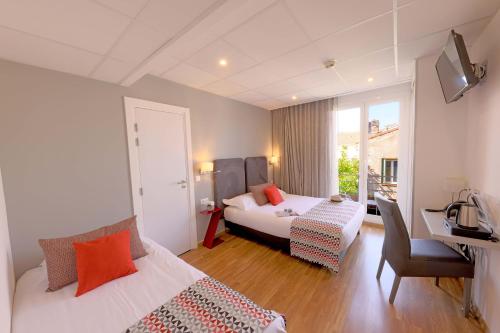 a hotel room with two beds and a desk at Hôtel Méditerranée in Calvi