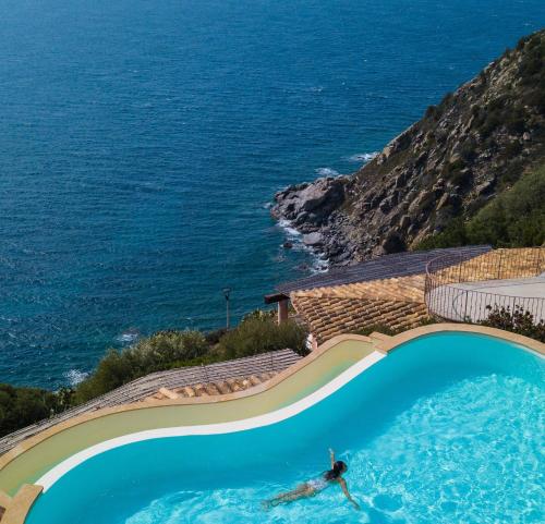 a person swimming in a swimming pool next to the ocean at Vista mozzafiato a picco sul mare Villa Patty in Torre delle Stelle
