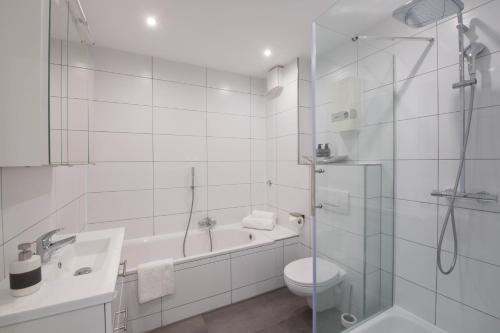 a white bathroom with a tub and a toilet and a shower at Luxury Luisenthal in Völklingen