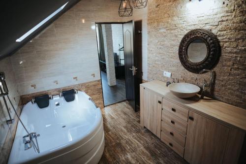 a bathroom with a tub and a sink and a mirror at Pensiunea La Lenuta in Onceşti