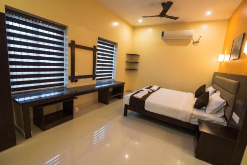 a bedroom with a bed and a desk and a window at Saffron Vilva in Puducherry