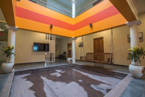 an empty lobby with a colorful ceiling and plants at Saffron Vilva in Puducherry