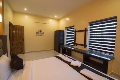 a bedroom with a bed and a desk and a window at Saffron Vilva in Puducherry