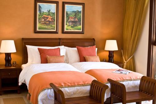 a bedroom with a bed with two chairs and two paintings at Eden Island Luxury Accommodation in Eden Island