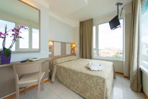 a hotel room with a bed and a desk and window at Hotel Cristallo in Riccione