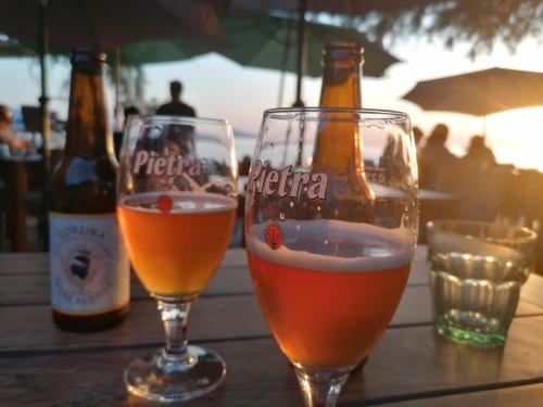 deux verres de bière assis sur une table avec des bouteilles dans l'établissement Casa di Ceppo, à Patrimonio