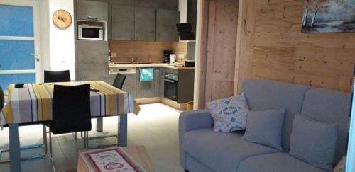 ein Wohnzimmer mit Couch und Küche in der Unterkunft Les balcons la haie des grisselles in Gérardmer