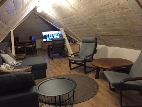 a living room with a couch and chairs and a tv at Babushka Noclegi in Białowieża