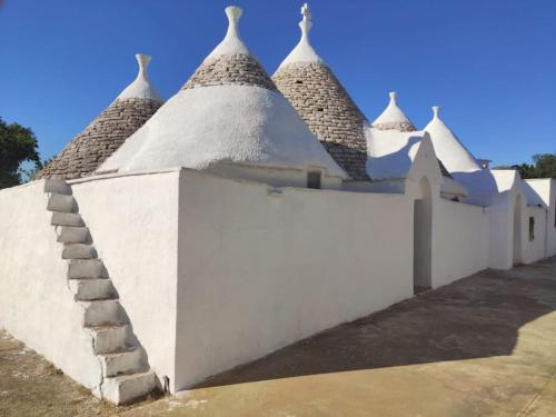 a white building with a staircase next to a wall at I Trulli D'a Ross in Ceglie Messapica
