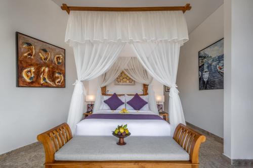 a bedroom with a bed with a canopy at Swan Paradise A Pramana Experience in Gianyar