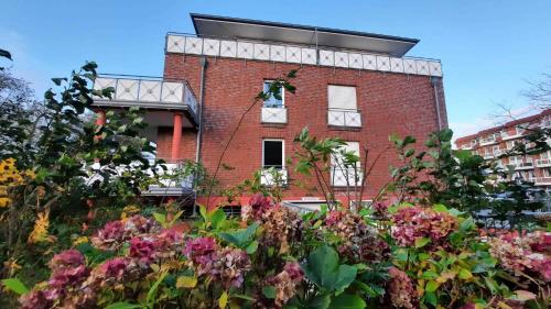 een bakstenen gebouw met bloemen ervoor bij Residenz Villa am Strand in Cuxhaven