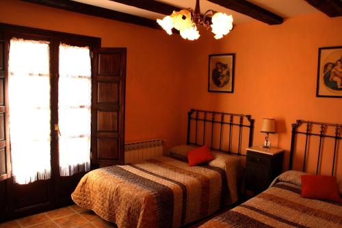 two beds in a bedroom with orange walls and a window at Hotel Rural El Rimero de la Quintina in Yanguas