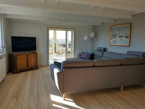 a living room with a couch and a flat screen tv at Idyllisk gård med ro, plads og havudsigt in Hesselager