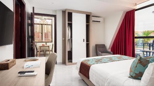 a hotel room with a bed and a desk and a table at Vakara Hotel Kep in Kep