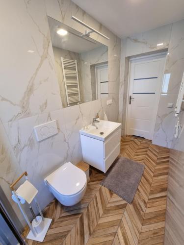 biała łazienka z toaletą i umywalką w obiekcie Willa Zachodni Brzeg w mieście Międzyzdroje