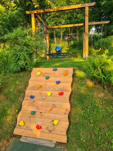 a wooden boardwalk with a playground in a yard at Domki Pod Horbem in Polańczyk