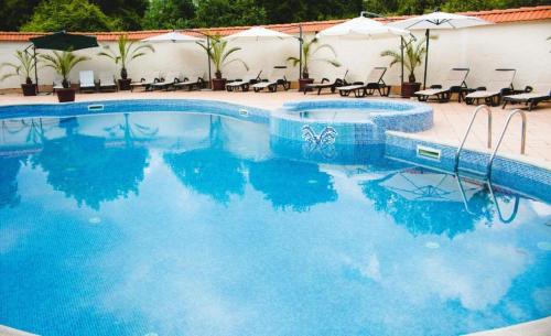 una piscina con acqua blu, sedie e ombrelloni di Family Hotel Shipkovo a Shipkovo