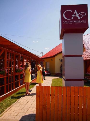 two women in yellow dresses walking in front of a building at Casa Ardeleneasca in Timişoara