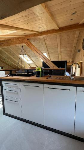 a kitchen with white cabinets and a wooden ceiling at Truma Swing Castelfondo in Castelfondo