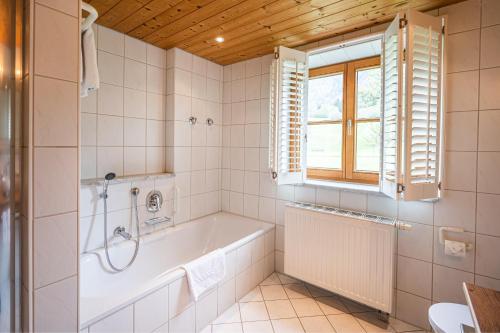 Un baño con bañera y ventana. en Landhaus Berktold, en Oberstdorf
