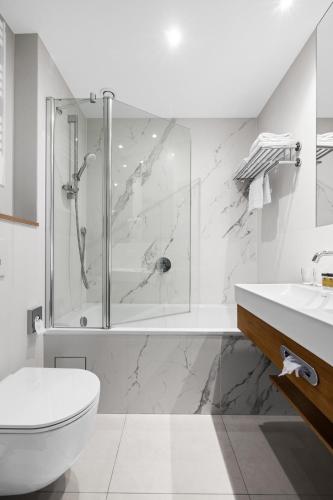 a bathroom with a shower and a toilet and a sink at Maloves Resort & Spa in Władysławowo