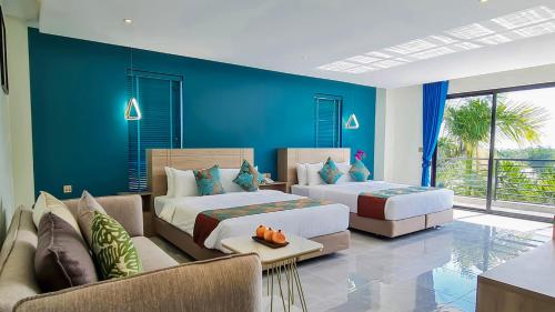 two beds in a room with a blue wall at Vakara Hotel Kep in Kep