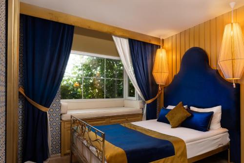 a bedroom with a bed with blue curtains and a window at La Capria Suite Hotel Alacati in Alacati