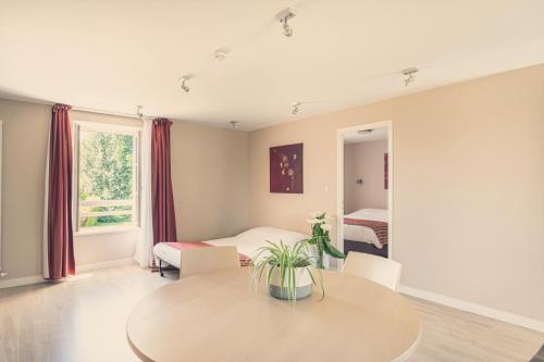 a living room with a table and a bedroom at La Pommeraie in Bruz