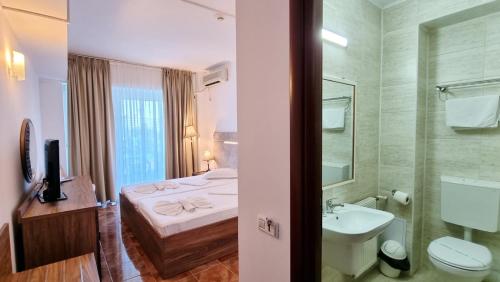 a bathroom with a bed and a sink and a toilet at Hotel Florida Mamaia in Mamaia