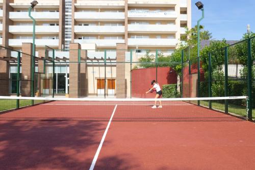 a woman playing tennis on a tennis court at Ibersol Spa Aqquaria in Salou