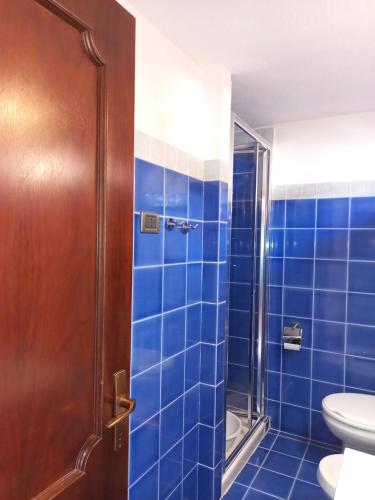 a blue tiled bathroom with a toilet and a shower at Lucky Apartment in Golfo Aranci
