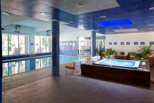 a swimming pool with a jacuzzi tub in a building at Ibersol Spa Aqquaria in Salou