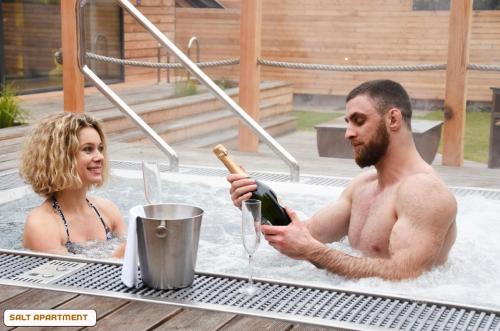 a man and woman in a hot tub with a bottle of wine at You and Me Apartments in Prosenická Lhota