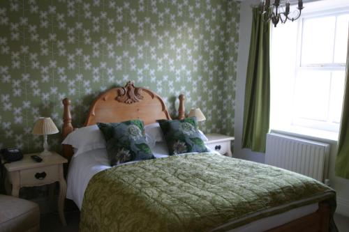 a bedroom with a bed with a green comforter at The Charles Bathurst Inn in Richmond