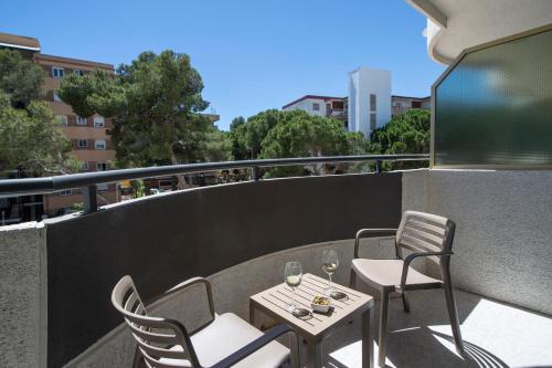 a patio with two chairs and a table with wine glasses at Hotel Salou Sunset by Pierre & Vacances in Salou