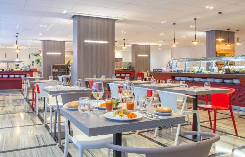 a restaurant with tables and chairs with food on them at Hotel Salou Sunset by Pierre & Vacances in Salou