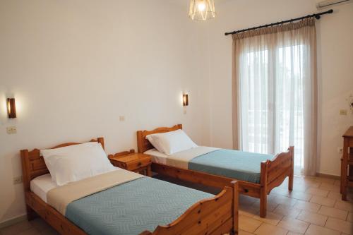 two beds in a room with a window at Pagonia Apartments in Arillas