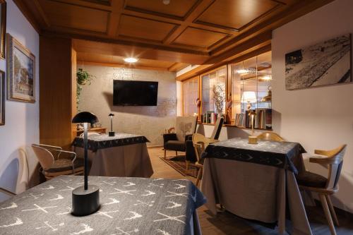 a room with two tables and chairs and a tv at Hotel Nele in Ziano di Fiemme