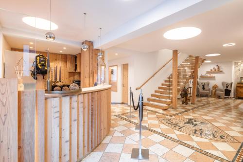 a kitchen and living room with a counter and stairs at Hotel Nele in Ziano di Fiemme