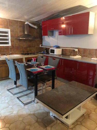 una cocina con armarios rojos y una mesa con sillas. en Studio avec jardin clos et wifi a Saint Pierre a 4 km de la plage en Saint-Pierre