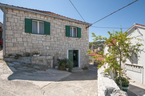 a stone house with green shutters at Apartments Gorana in Splitska