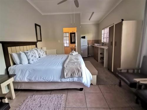 a bedroom with a large white bed and a kitchen at Tourist Lodge Gansbaai in Gansbaai