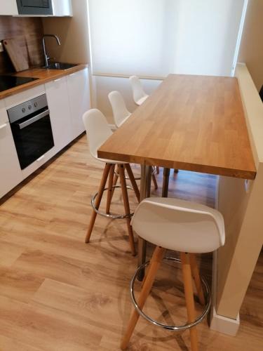 a kitchen with a wooden table and white chairs at Apartamento Costa II con Parking exterior comunitario in Zumaia