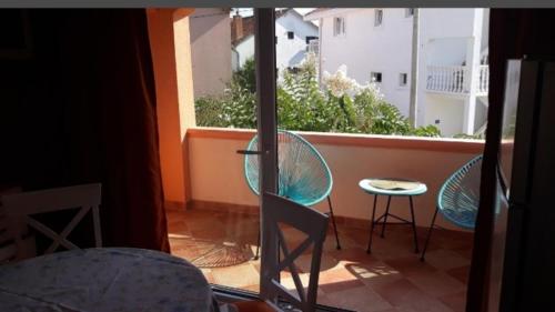蒂瓦特的住宿－Apartmani Tanja，阳台配有两把椅子和一张桌子,还有一个窗户。